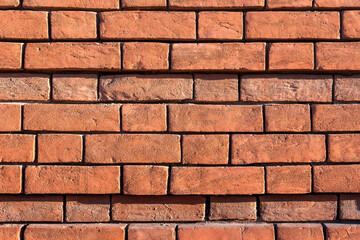 Ancient red brick masonry on the wall of a residential building. Natural stone background and texture.