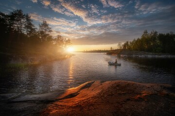 Sunny summer sunset on Lake Ladoga. Colorful clouds. Quiet and peaceful evening. Beautiful light falls on rocks and moss. Ladoga. Republic of Karelia.