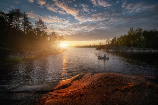 Sunny summer sunset on Lake Ladoga. Colorful clouds. Quiet and peaceful evening. Beautiful light falls on rocks and moss. Ladoga. Republic of Karelia.