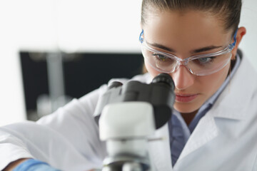 Female chemist investigate sample under microscope equipment in lab