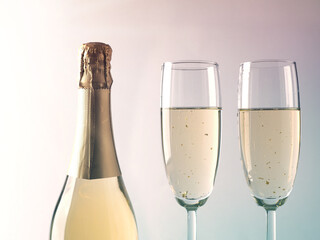 Two glass of sparkling wine with gold foils and a bottle, New Year or holidays concept