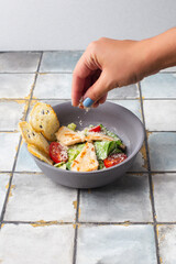 Healthy organic Chicken Caesar Salad with grilled chicken and croutons woman hand