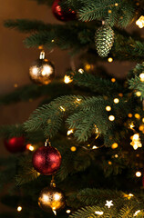 Christmas golden and red balls hanging on branch of spruce tree. Festive background. Holiday concept.