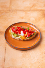 tomato bruschetta with avocado guacamole, basil and olive oil on served on brown round ceramic plate