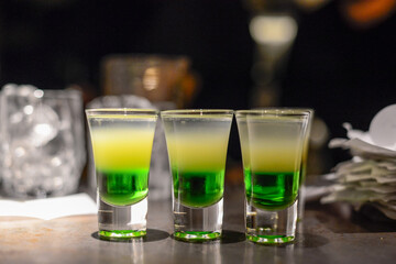 three shots green Mexican on the bar

