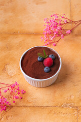 dessert tiramisu with berries on brown background with pink flowers