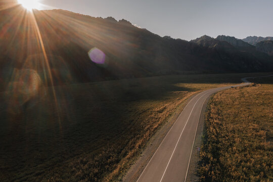 View from a drone asphalt road among the mountains at sunset