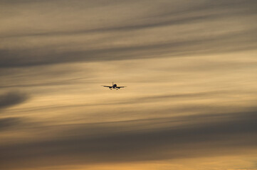 airplane in the evening sky in luminous horizon.