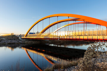 curved red arches of the highway bridge over the river Lech near Augsburg in the light of the evening sun