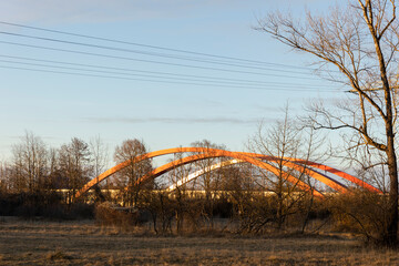 curved red arches of the highway bridge over the river Lech near Augsburg in the light of the evening sun