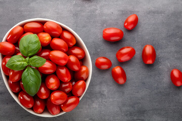 Fresh tomatoes in bowl on pastel table.