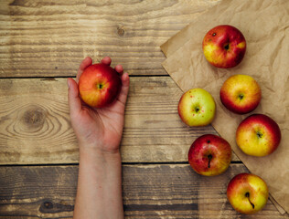 A ripe juicy apple is held by a female hand on a wooden background. A healthy fruit.Healthy eating and diet.