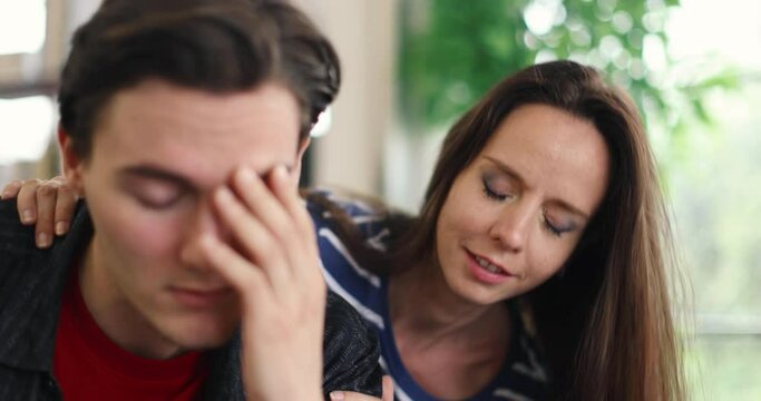 Close up video shot of Millennial Caucasian supportive wife sitting touching talking soothing and comforting solving problem for stress depress despair serious upset unhappy husband having headache.