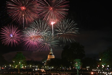 Multicolored firework near the old principal Buddha image,old pagoda on the celebration Loy Krathong festival  at the Wat Mahathat Temple in Sukhothai Historical Park.It is a tradition around ancient 