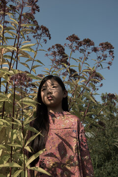 fine art portrait of asian young woman in shadows of flowers in spring