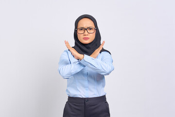 Portrait of annoyed young Asian woman crossing hands makes stop gesture, demonstrates rejection isolated on white background