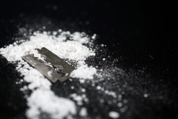 Razor Blade on drug powder on reflection black background.Copy space.