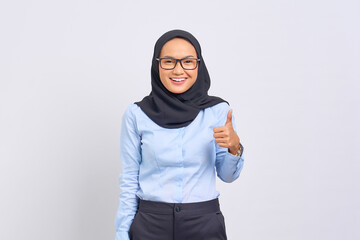 Portrait of smiling young Asian woman showing thumbs up gesture, Approving expression looking at the camera with showing success isolated on white background