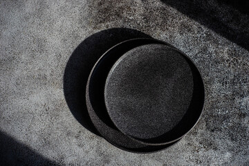 Overhead view of two black stoneware plates on a grey table