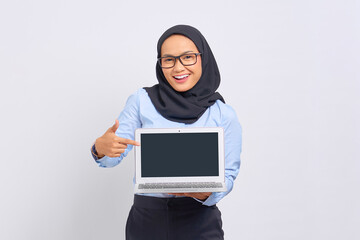 Portrait of smiling young Asian woman pointing fingers at a blank screen of a laptop, with copy space for presenting product isolated on white background