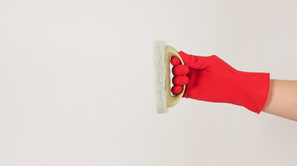 A hand is holding a scourer pad with the handle and wears a red latex glove on black background.