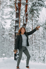 A happy girl with a short haircut walks in the forest after a snowfall and holds a pine branch and admires the incredible nature.Winter fairy tale in the forest.Christmas holidays, outdoor activities