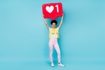 Full length photo of funky young brunette lady hold pinata wear t-shirt trousers footwear isolated on blue background