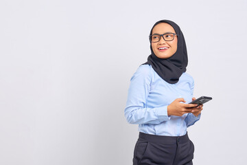 Portrait of smiling young Asian woman using a mobile phone and looking away isolated on white background