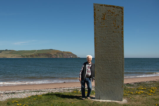 Man leaning against Emigration Stone, Cromarty, Highlands, Scotland, UK