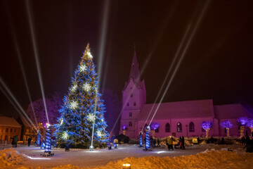 Christmas tree with lights outdoors at night in Dobele, Latvia. Church on background. New Year Celebration