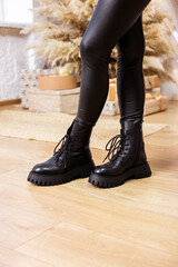 Womens winter black leather boots with legs on a studio background. New collection of shoes for stylish ladies