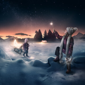 Two little girls light the stars in the night sky in winter