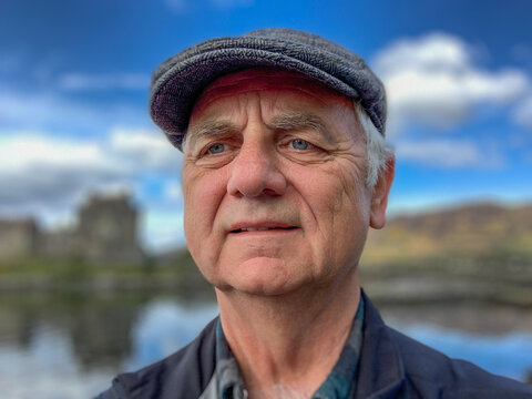 Portrait of a man wearing a flat cap standing in rural landscape , Inner Hebrides, Scotland, UK