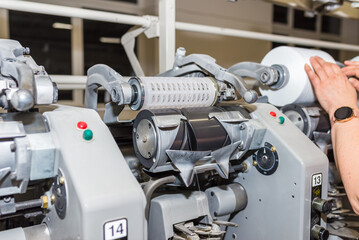 Cotton Yarn Production in a Textile Factory. Woman's hands worker in work. Row of automated machines for yarn manufacturing. Modern Textile Plant.Selective focus.