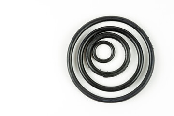 Black hydraulic and pneumatic o-rings in different sizes on a white background. O-rings for hydraulic connections. Rubber seals for sanitary ware. Copy space