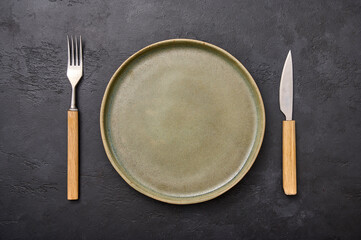 Empty green plate with fork and knife on black graphite background. Top view design concept, copy space - Powered by Adobe