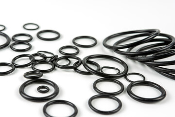 Black hydraulic and pneumatic o-rings in different sizes on a white background. O-rings for hydraulic connections. Rubber seals for sanitary ware. Copy space
