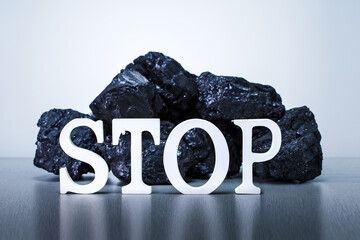 Stop coal mining concept. Word STOP with Coal Stack on grey background.