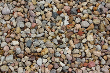 Small colored dry stones on gravel beach background texture