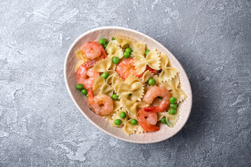 Bowl of italian farfalle pasta with shrimps and green peas
