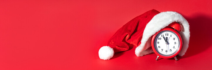 Red clock with Christmas Santa hat. Time for Christmas shopping concept. Blank copy space for text.