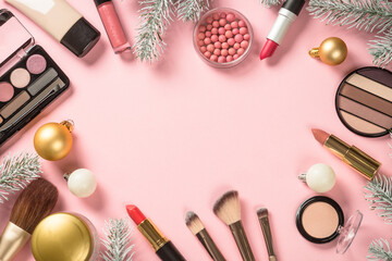 Obraz na płótnie Canvas Make up cosmetic products and christmas decorations at pink. Flat lay image with copy space.