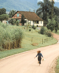 mulher correndo em estrada rural com casa enxaimel ao fundo, em Pomerode, Santa Catarina