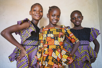 Three african girls stand by the wall