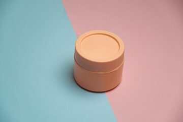 studio photo of salmon colored round box standing in pink and blue font,two color backgrounds object , studio photo