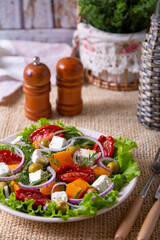 Warm salad with pumpkin, feta cheese, sun-dried tomatoes, olives, arugula and red onion. Close-up.