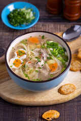 Soup with chicken, noodles, potatoes, quail eggs and carrots. Seasoned with onions and parsley. Close-up.