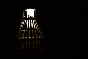 Fototapeta na wymiar A lamp with lampshades of a cage made from bamboo in low lights. Selective focus points