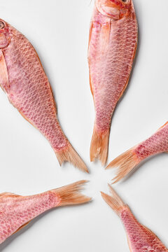Five air-dried red mullets tails arranged on white background