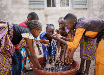 Group of african children play with fresh water - obrazy, fototapety, plakaty